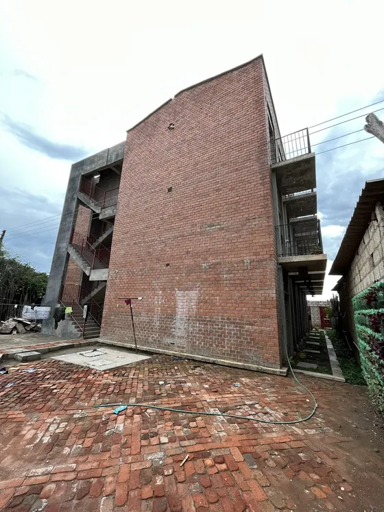 The finished brick building seen from a paved brick courtyard.